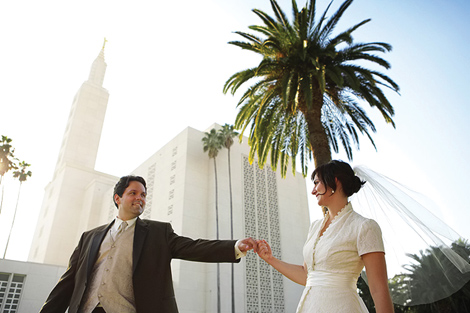 The bride and groom hold hands outside the church in Los Angeles, surrounded by Palm Trees