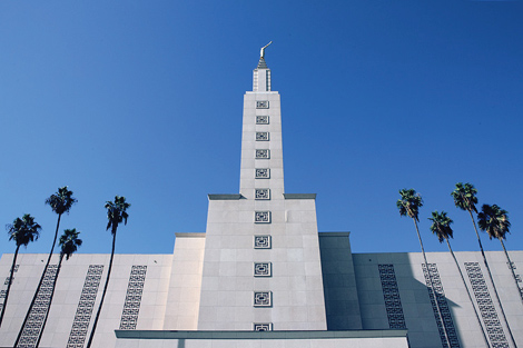 The church spire stands out against the beautiful blue sky and palm trees of Los Angeles