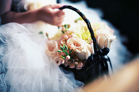 The flower girl holds a basket of flowers, including peach roses