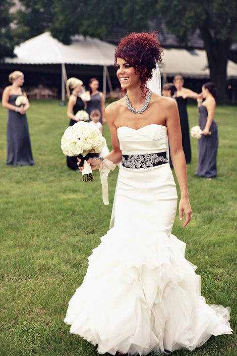 The bride laughs and poses for a portrait, holding her white rose bouquet at Greenville Country Club