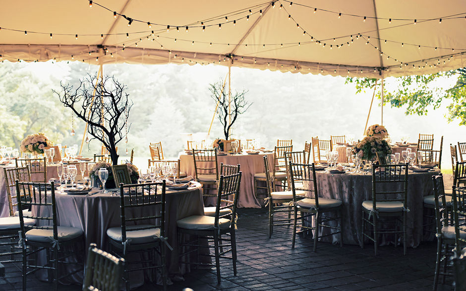 Lights strung through the tent add a beautifully elegant and summery mood for this outdoor wedding at Greenville Country Club; small tress adorned with crystals make elegant and unique centerpieces