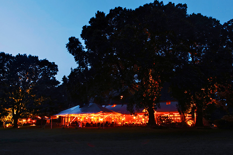 The tent glows in the evening light after a beautiful summer wedding at Greenville Country Club in Delaware