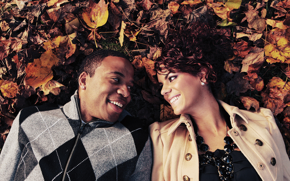 The copule lays in the fall leaves for their engagement photos at Winterthur in Delaware