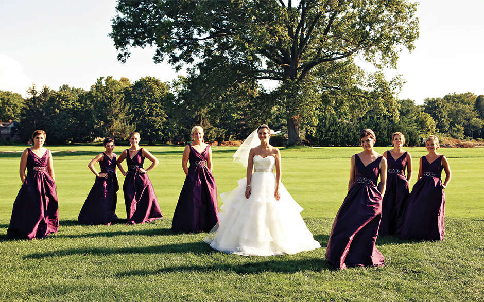 The bridal party poses with the bride on a golf course at the Moorestown Field Club, wearing long purple gowns