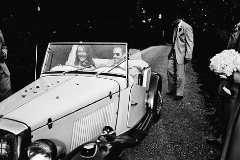 The bride and groom arrive at the carriage house of rockford park in delaware in style riding in a classic antique car from antique automotive, and are greeted by the wedding party.