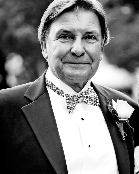 Father of the bride poses in Rodney Square in Wilmington Delaware for a black and white portrait while wearing a bowtie.
