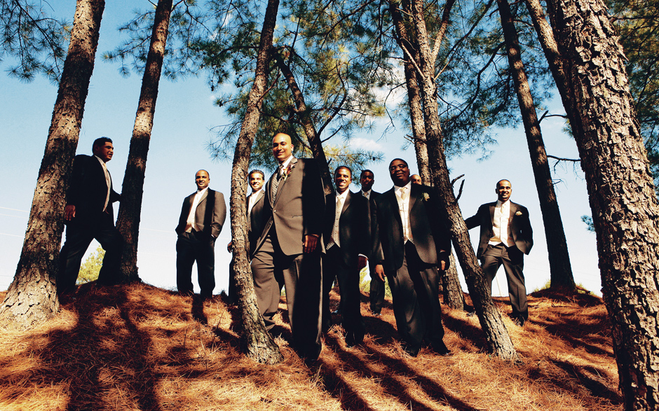 Groomsmen pose for photos amongst pine trees on a sunny day outside, photographed by Peter Van Beever