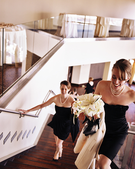 The bridal party, wearing strapless black dresses, walk up the stairs before the ceremony at the State Room in Boston