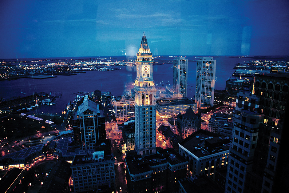 The Boston skyline, harbor, and clock tower downtown look enchanting in the evening light, as seen from the State Room, wedding photography by Peter Van Beever
