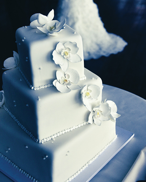 A three layer square wedding cake is adorned with white orchid flower details, looking simple and elegant for this Boston wedding