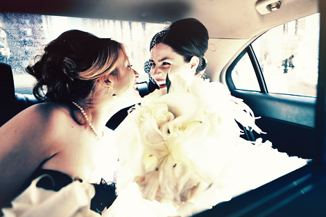 The bride and her maid of honor laugh in the car on their way to the wedding in Boston