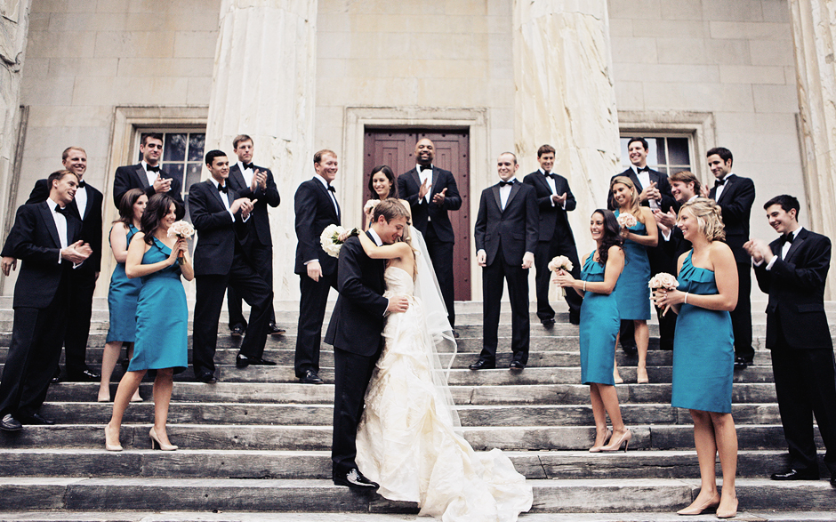 The bride and groom are surrounded by the bridal party, wearing tuxedos and blue cocktail dresses, on the steps of the bank building in Philaelphia