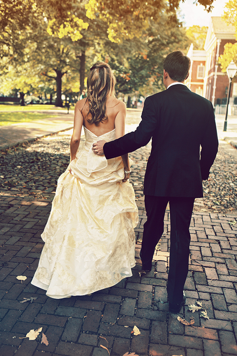 The bride and groom walk together on the cobblestone streets on a warm summer day in Philadelphia after their wedding