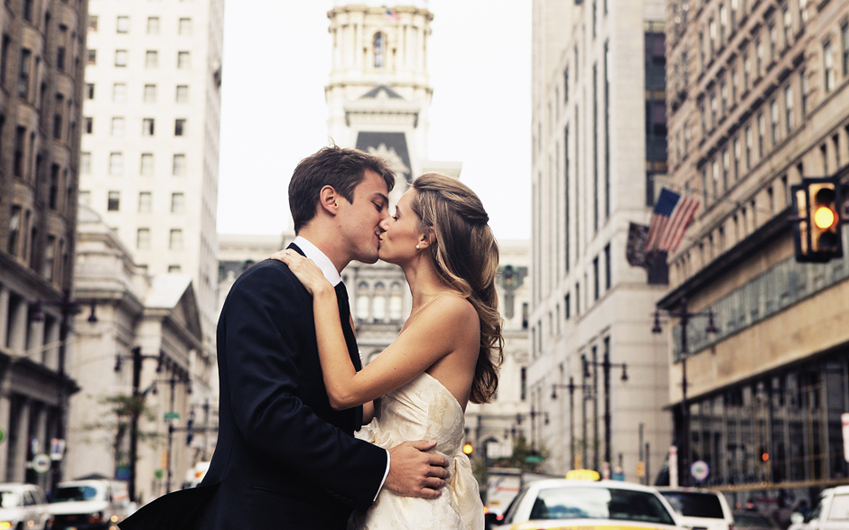 The bride and groom kiss on Broad Street in front of City Hall in Philadelphia