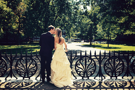 The bride and groom kiss in front of an intricate iron fence in Philadelphia
