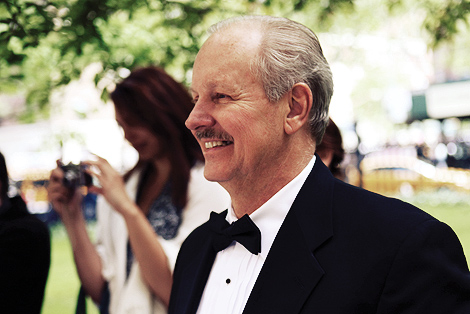 The father of the groom looks on as the bride and groom pose for photos