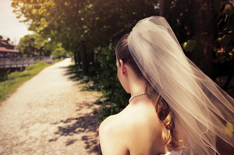 The bride walks along the path at the Aldie Mansion on her beautiful wedding day, with her veil fluttering in the breeze