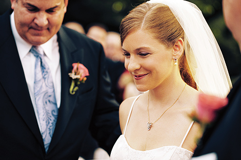 The bride looks happy surrounded by her bridal party as her father gives her away