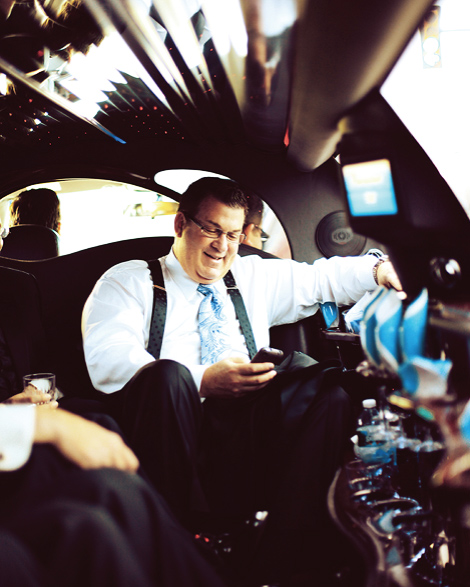 The father of the bride checks his phone on the limo ride to the ceremony, to take place at the Aldie Mansion in Pennsylvania