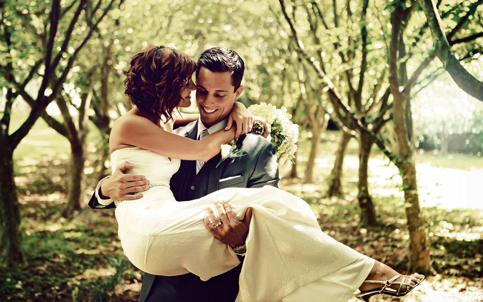 The groom holds the bride amongst the green tress on a warm September day at Appleford Estate, wedding photography by Peter Van Beever