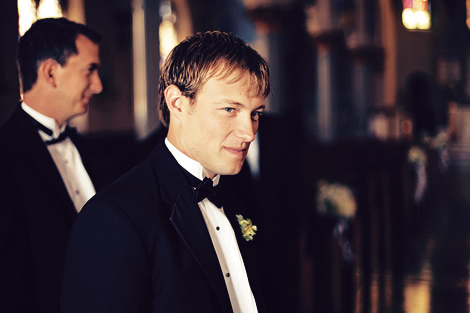 A groomsman smiles and waits before the wedding ceremony